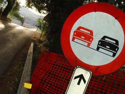 Maremma, Via di Rimigliano.
Dialogo tra tridimensionalità  e bidimensionalità . La raffigurazione stilizzata e piatta sul cartello ci tenta ad una proiezione temeraria sulla sinistra del segnale, su quell'invitante saliscendi stradale. E l'inquadratura sghemba ci disnibisce ulteriormente, narcotizzando la reale determinazione dei rischi spaziali e viari.